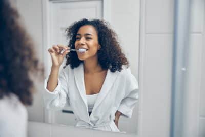 adult woman looking in the mirror and brushing her teeth