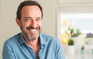 Middle-aged man in blue button up smiling with teeth