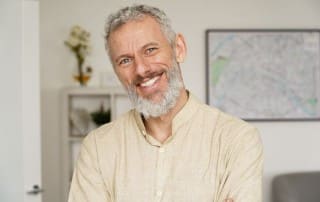 Middle aged man in off-white button up smiling